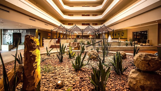 Un hall d’hôtel doté d’un espace salon central, d’une grande sculpture en pierre et d’un design de plafond moderne.