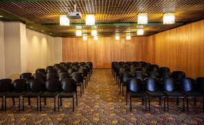 A conference room with rows of chairs, a projector, and a patterned carpet. - Garden Court Kimberley (Kimberley)