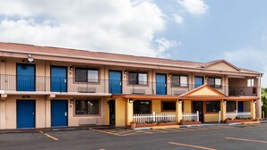 A motel with a two-story structure, a covered front porch, and a parking lot. - Red Carpet Inn (Elkton)