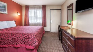 A hotel room with a bed, a dresser, a desk, a chair, a television, and a window with curtains. - Red Carpet Inn (Elkton)