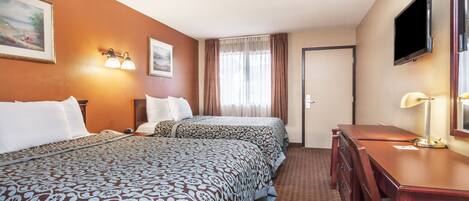 A hotel room with two beds, a desk, a chair, a TV, and a window with curtains.
