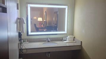 Un bagno d'albergo con un lavabo, uno specchio e un portasciugamani.