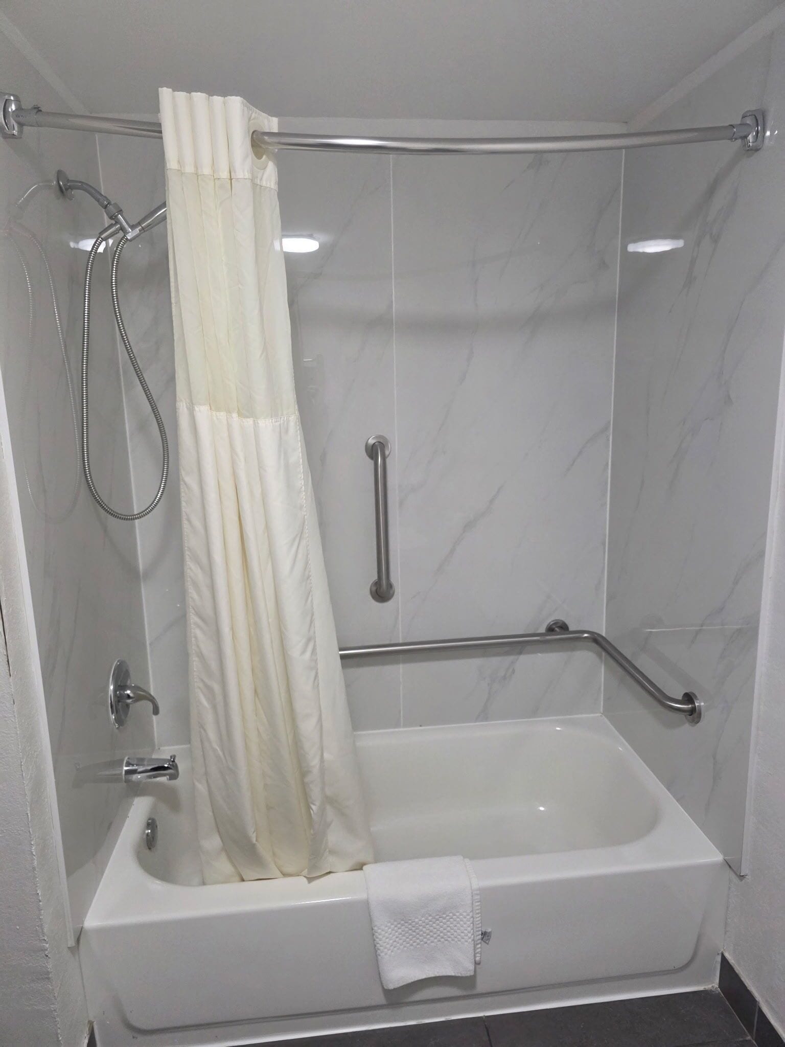 Un baño moderno con bañera, ducha y barra de apoyo.