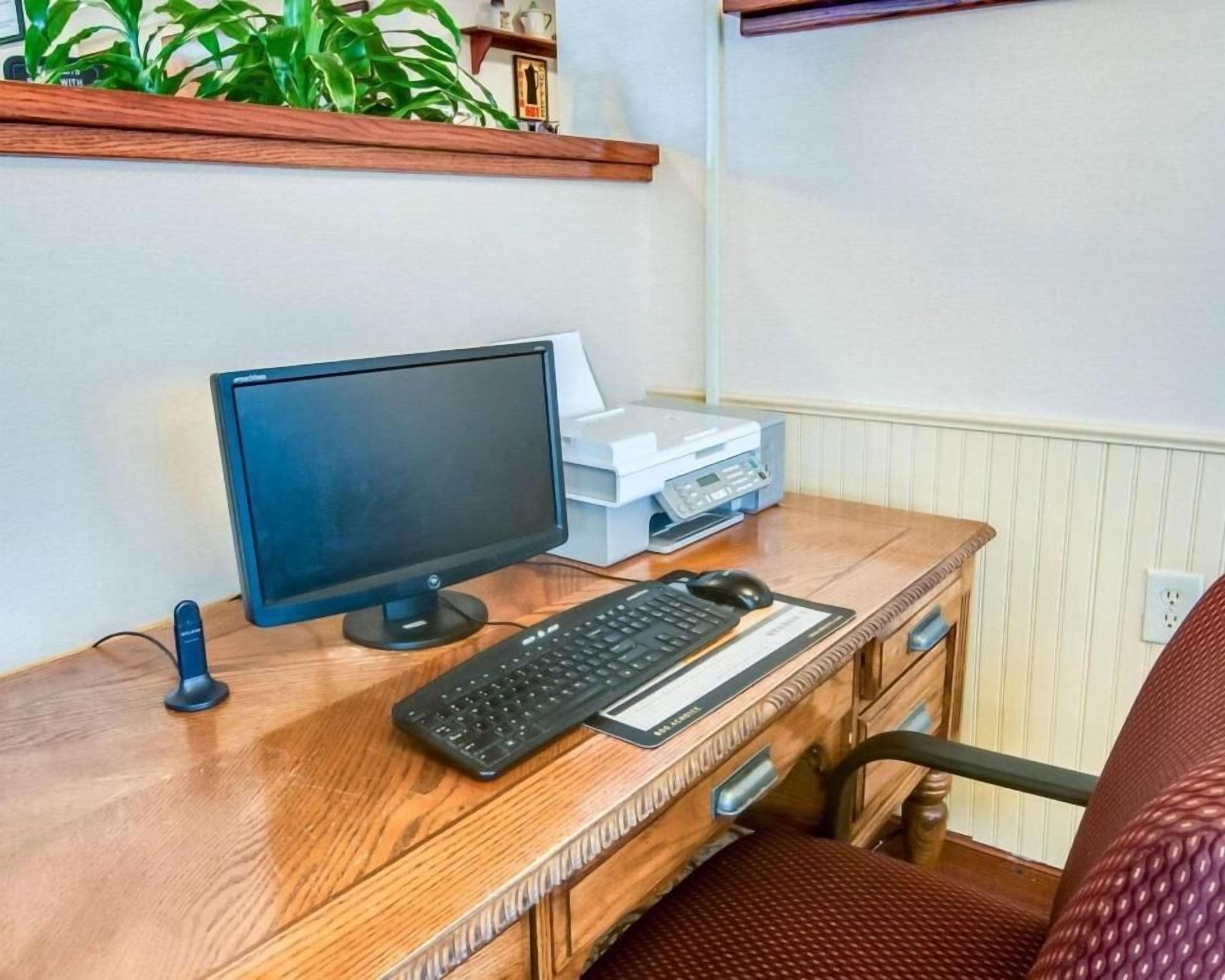 Una scrivania in legno con un monitor per computer, tastiera, mouse e stampante.