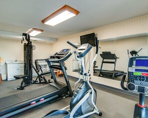 Uma academia com esteiras, elíptico e bicicleta ergométrica, equipada com mostradores digitais e aparelhos de musculação.