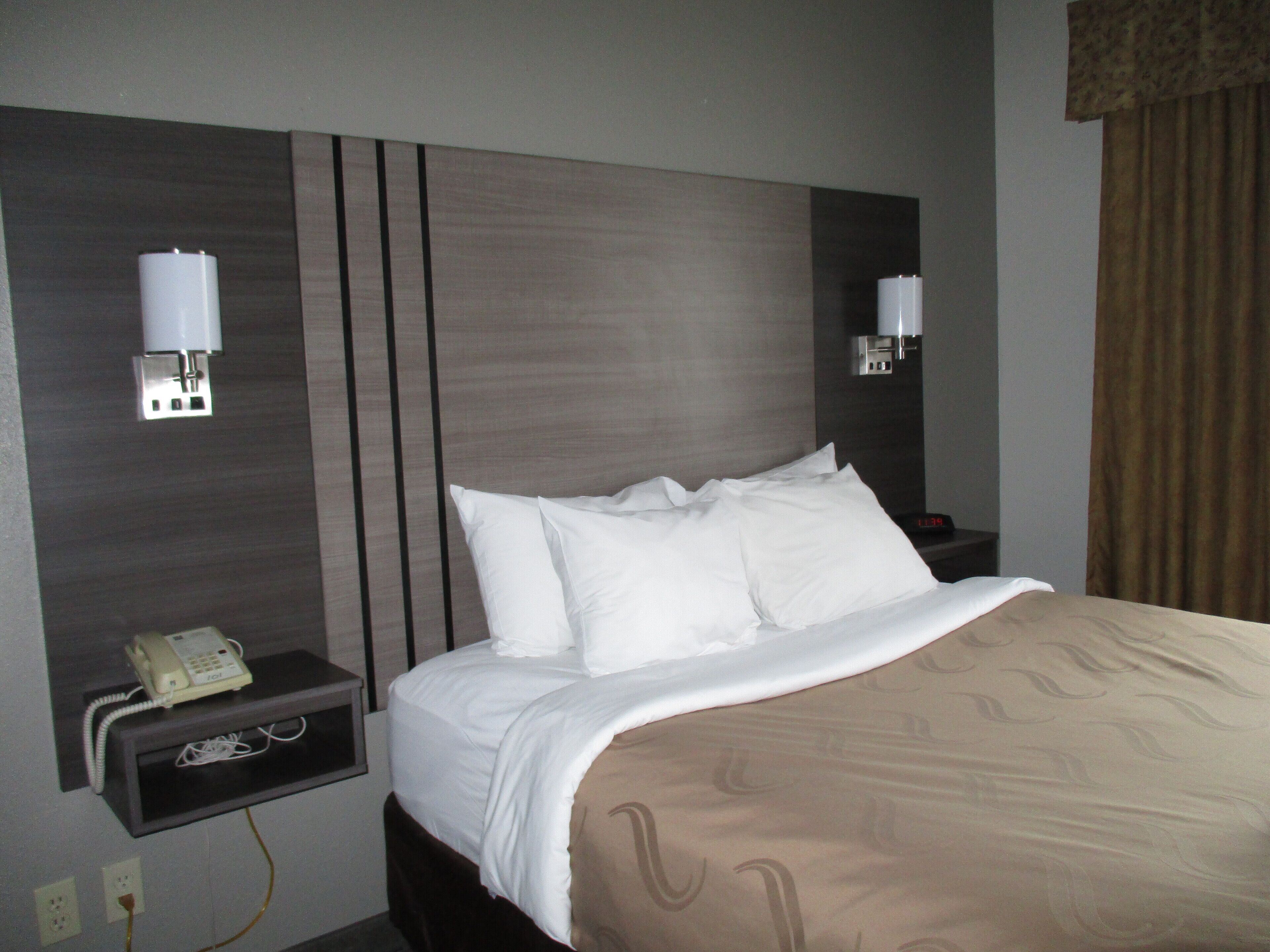A hotel room with a bed, bedside lamps, a phone, and a nightstand.