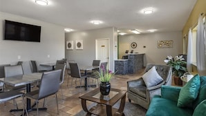 A spacious living area with a dining table, chairs, a sofa, and a TV mounted on the wall. - Quality Inn Kirksville (Kirksville)