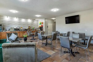 A modern dining area with a kitchen in the background, a flat-screen TV mounted on the wall, and a comfortable seating arrangement.