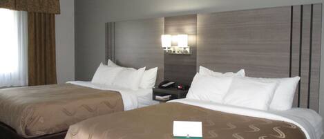 Une chambre d’hôtel avec deux lits, une table de chevet et une lampe fixée au mur.