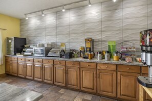 A modern kitchen with a granite countertop, wooden cabinets, and a textured backsplash.