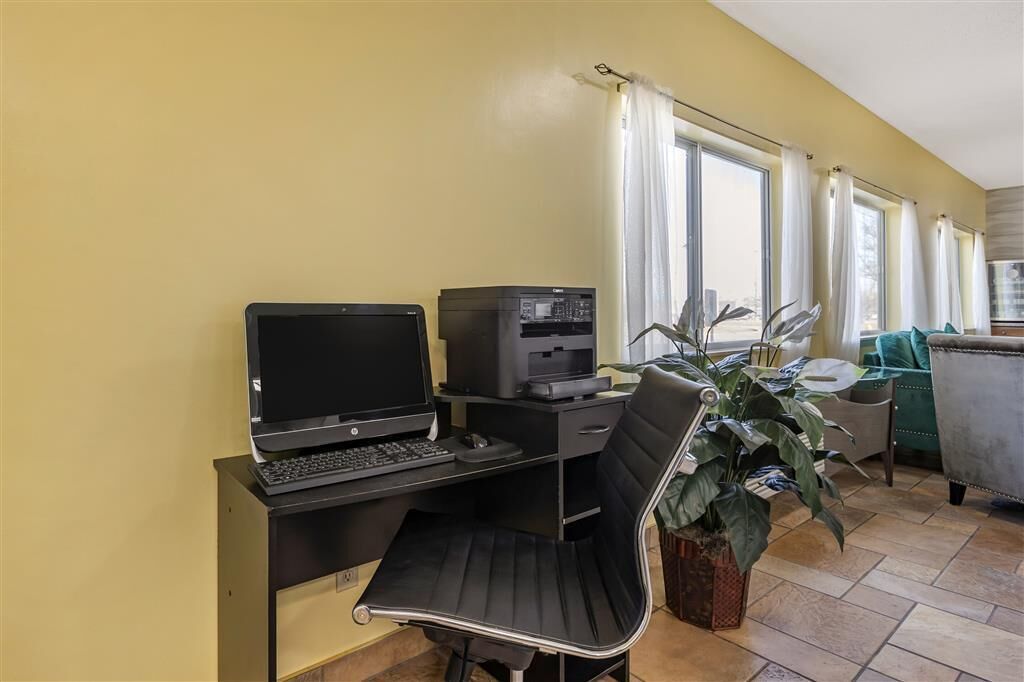 Espaço compacto com escrivaninha, laptop, impressora e uma planta em vaso.