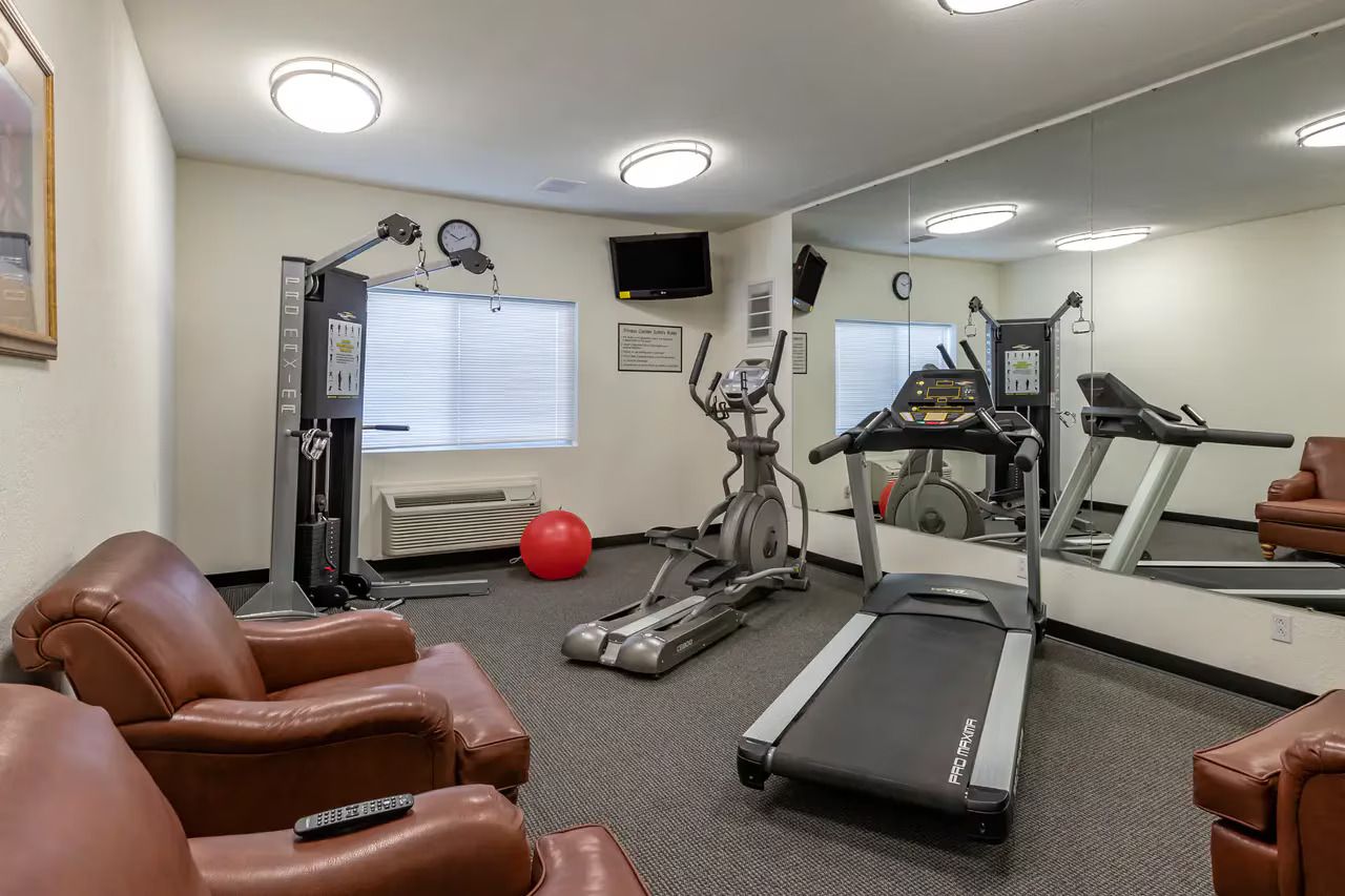 A fitness room with a treadmill, elliptical, stationary bike, and exercise balls.