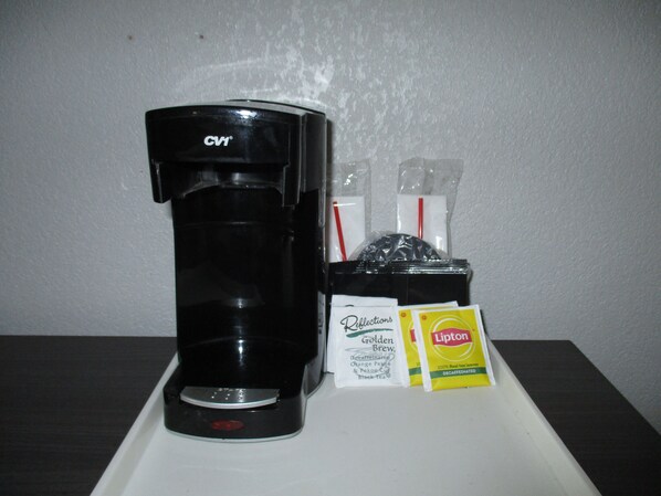 Une machine à café, des sachets de thé Lipton et un paquet de café décaféiné.