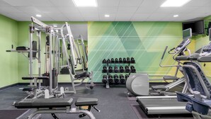 Ein Fitnessstudio mit Trainingsgeräten, Laufbändern und einem an der Wand befestigten Fernseher.