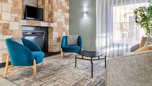 Ein Wohnzimmer mit Kamin, zwei blaue Sessel, ein graues Sofa und einem kleinen Tisch.