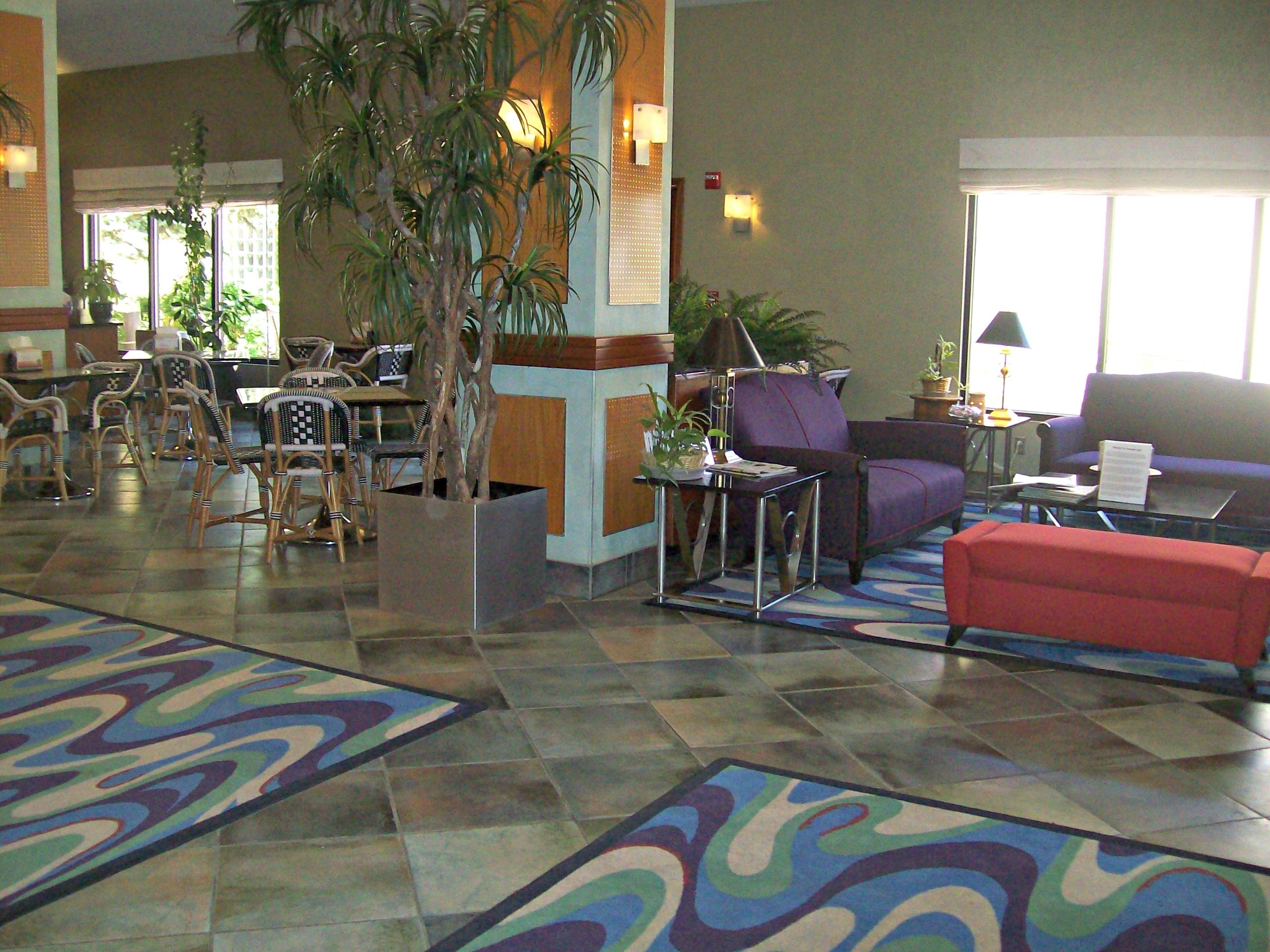 A hotel lobby with a reception desk, seating area, and a large window.