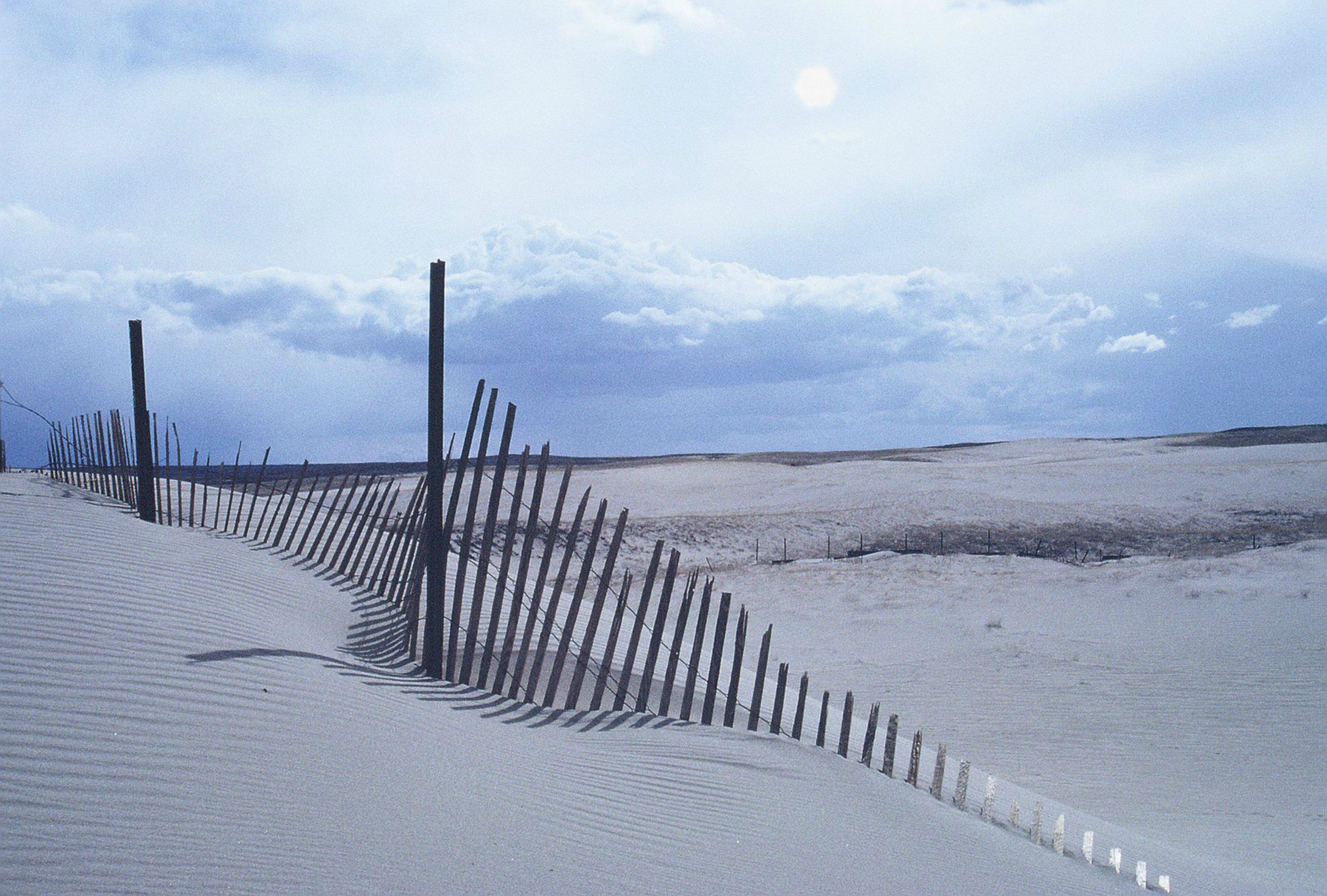 A snow-covered landscape with a fence and a clear sky.
