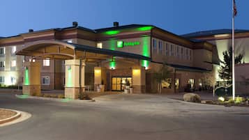 A Holiday Inn hotel with a covered entrance, outdoor seating, and a flagpole.