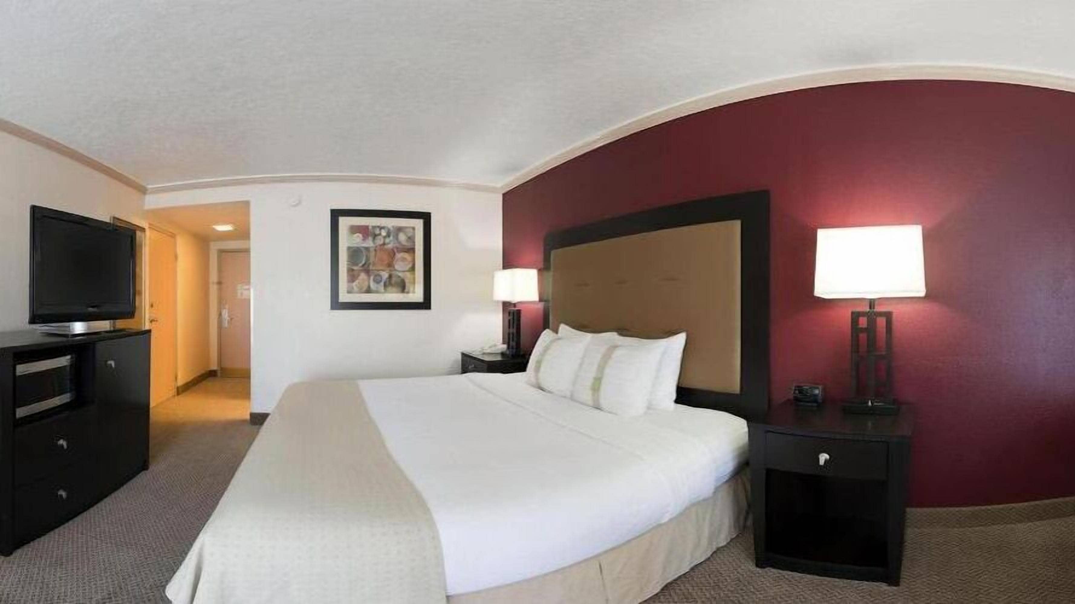 Une chambre d’hôtel avec un grand lit, une télévision, un bureau et une lampe.