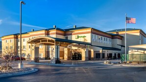 A Holiday Inn Express hotel with a covered entrance, a flagpole with an American flag, and a clear sky. - Holiday Inn Rock Springs by IHG (Rock Springs)
