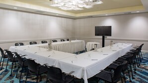 A conference room with a long table, chairs, a projector screen, and a chandelier. - Crowne Plaza Ventura Beach by IHG (Ventura)