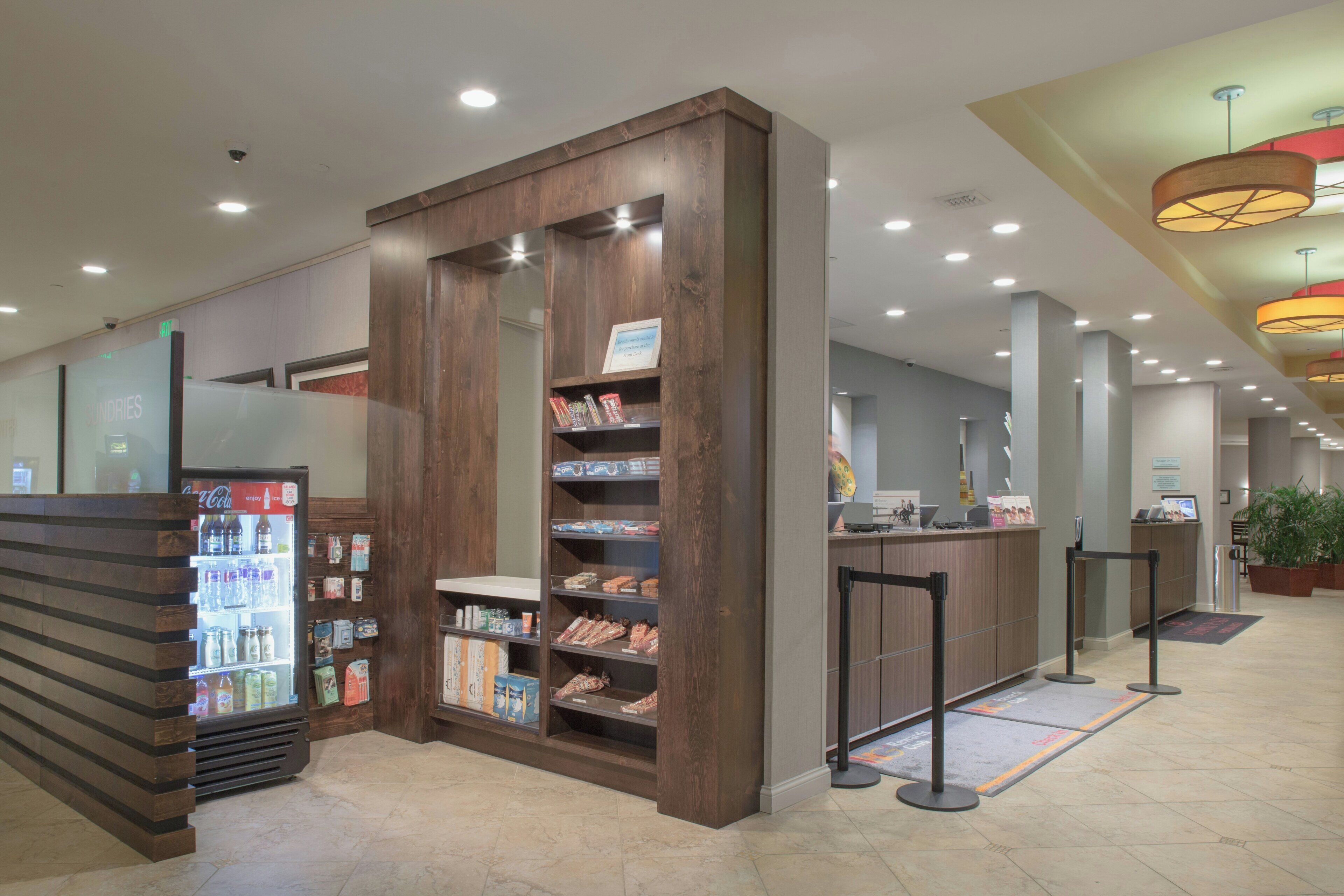 A hotel lobby with a self-service kiosk, a refrigerator with beverages, and a reception desk.