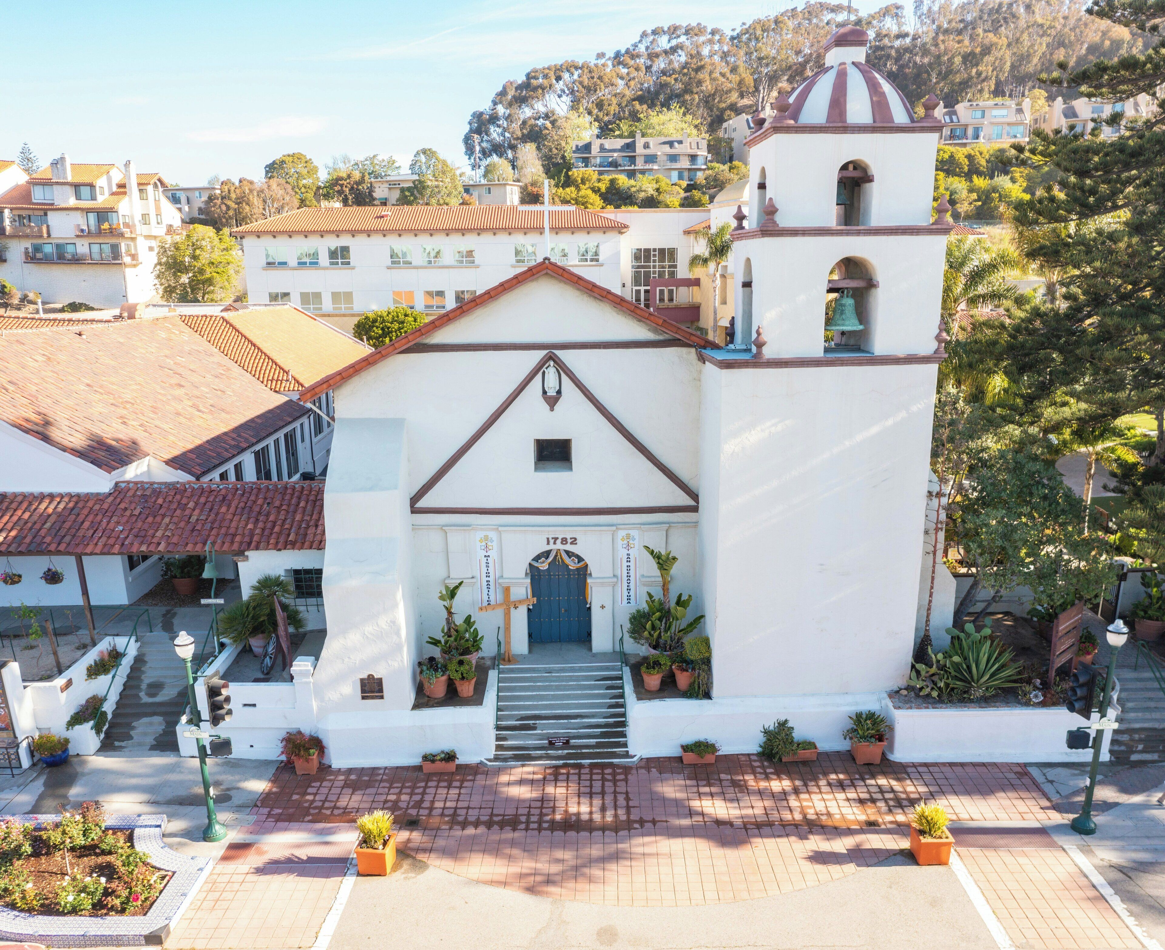 A white church with a bell tower, a blue door, and steps leading up to the entrance.