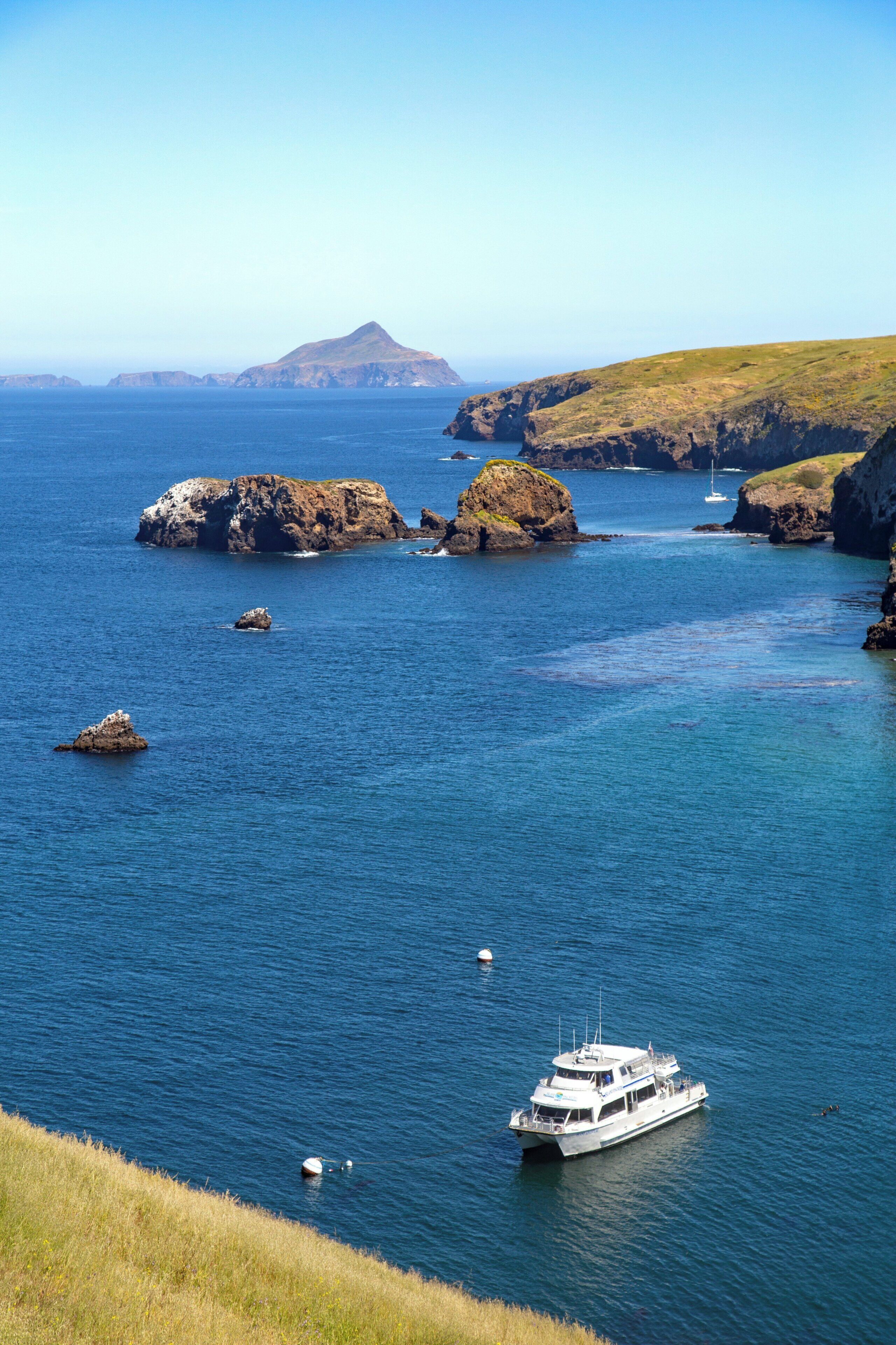 A coastal landscape with a boat in the foreground and rocky outcrops in the water.