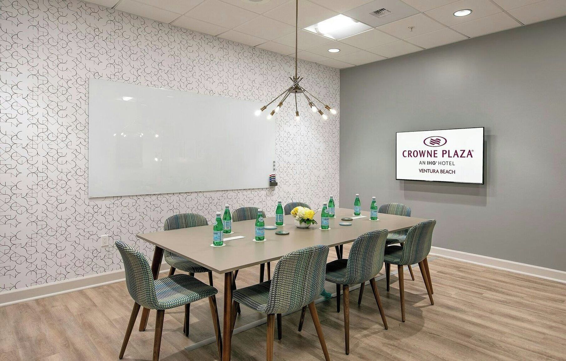 A conference room with a whiteboard, a chandelier, and a sign for Crowne Plaza.