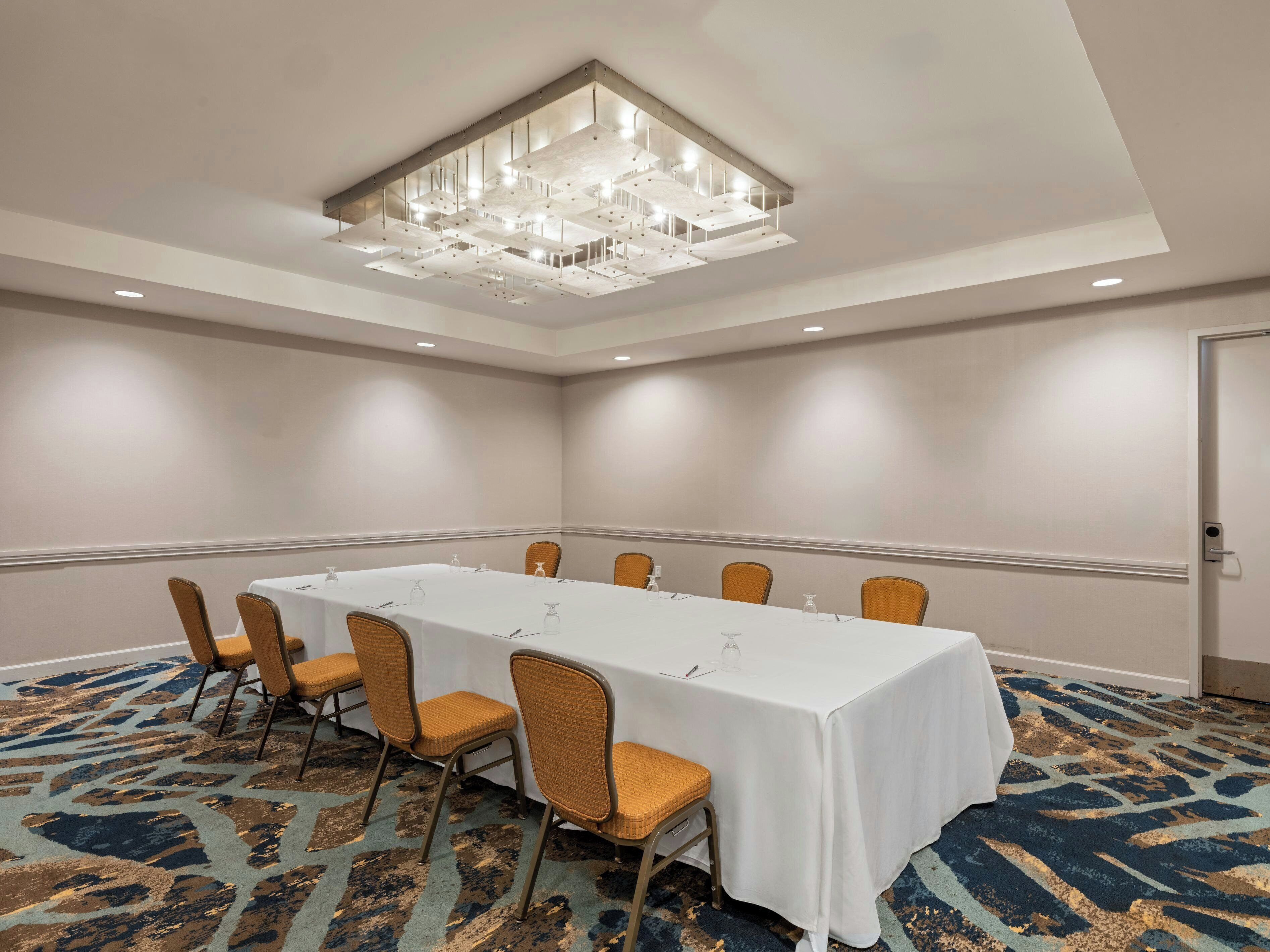 A conference room with a long table, chairs, and a chandelier.