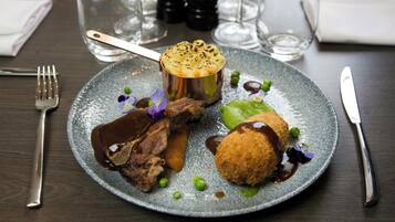A plate of food with a variety of items including a meat dish, a potato dish, and some greens.