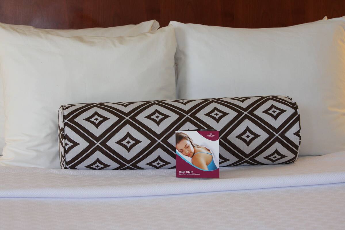 A bed with a patterned pillow and a box labeled "Sleep Tight" on a white bedspread.