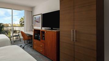 Une chambre d’hôtel comprenant un lit, un bureau avec une chaise, une télévision, une armoire et un balcon avec vue.