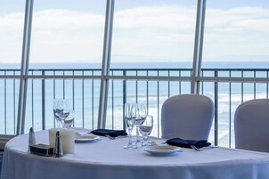 A table set for dining with a view of the ocean through large windows.