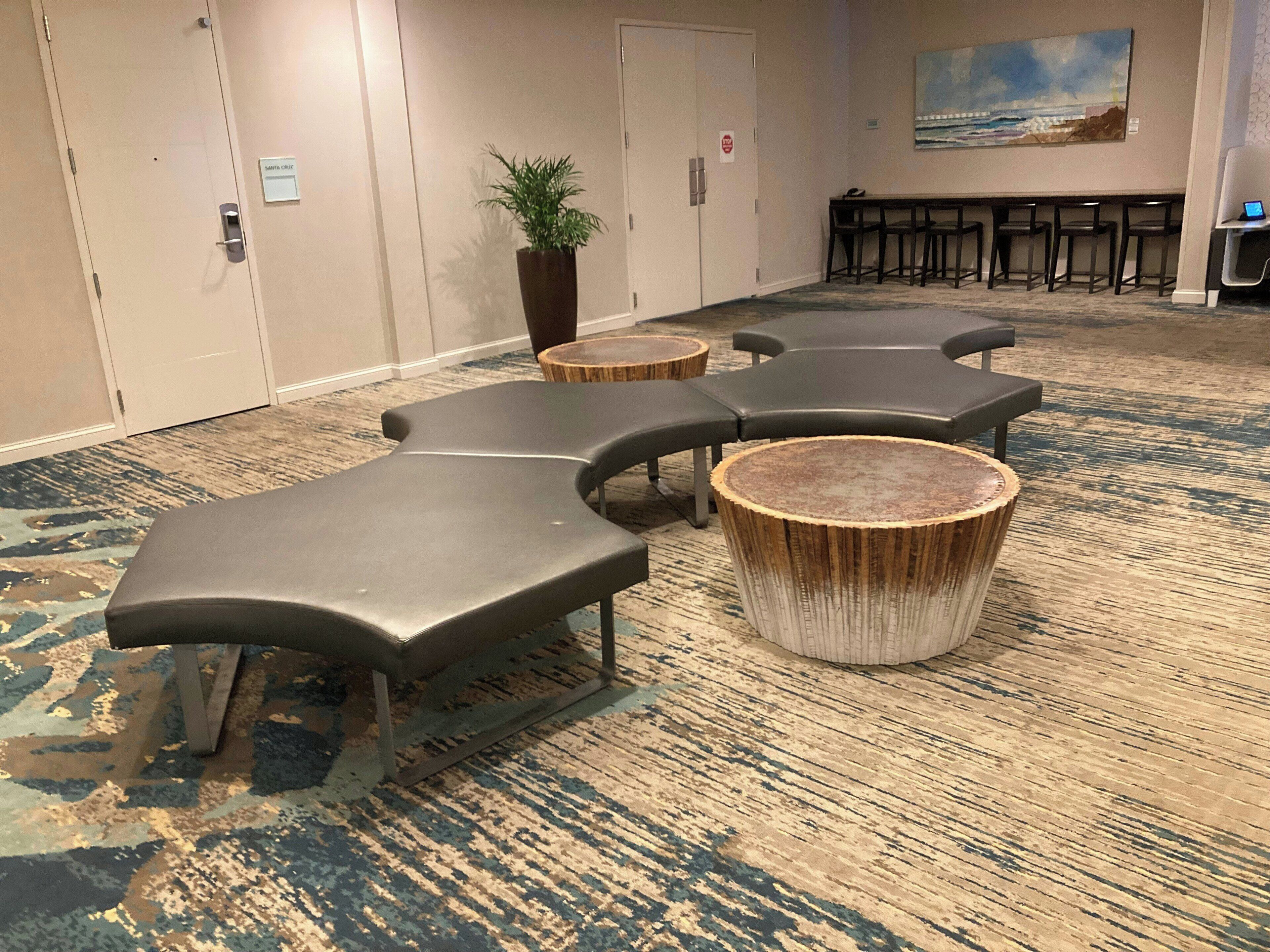 Habitación de hotel con zona de estar que incluye sillones y mesas de madera redondas.