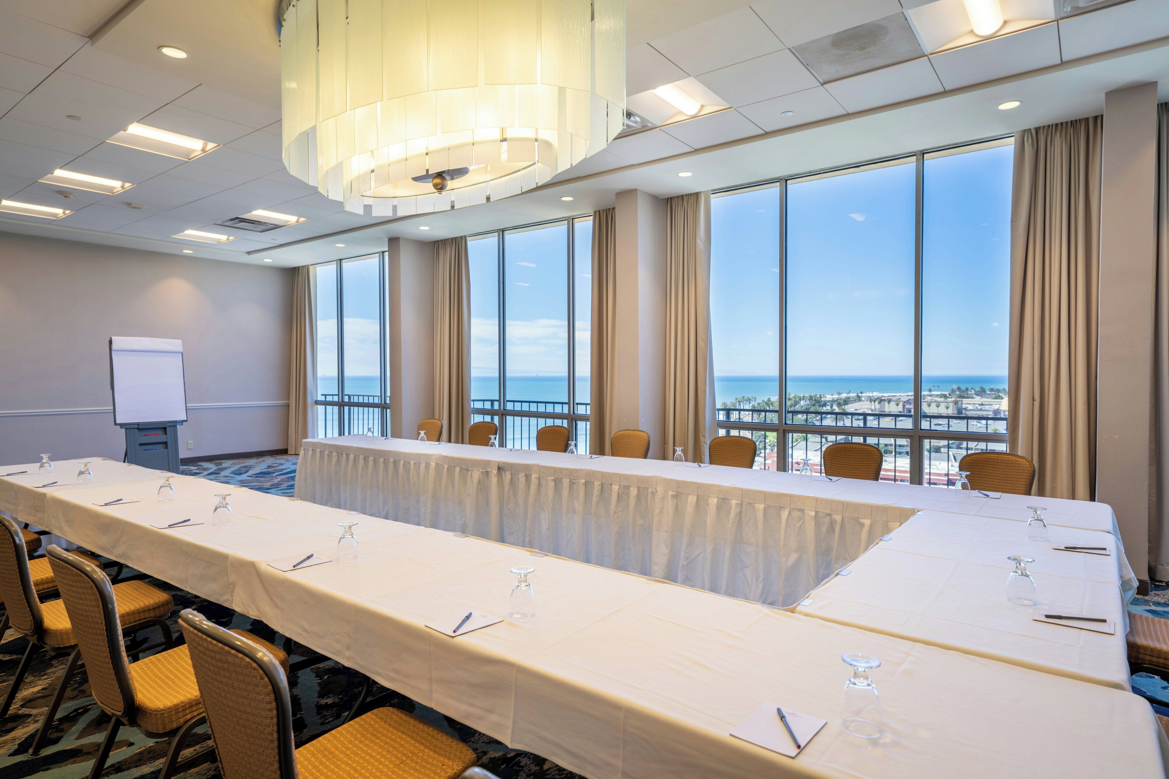 A conference room with a long table, chairs, and a view of the ocean.