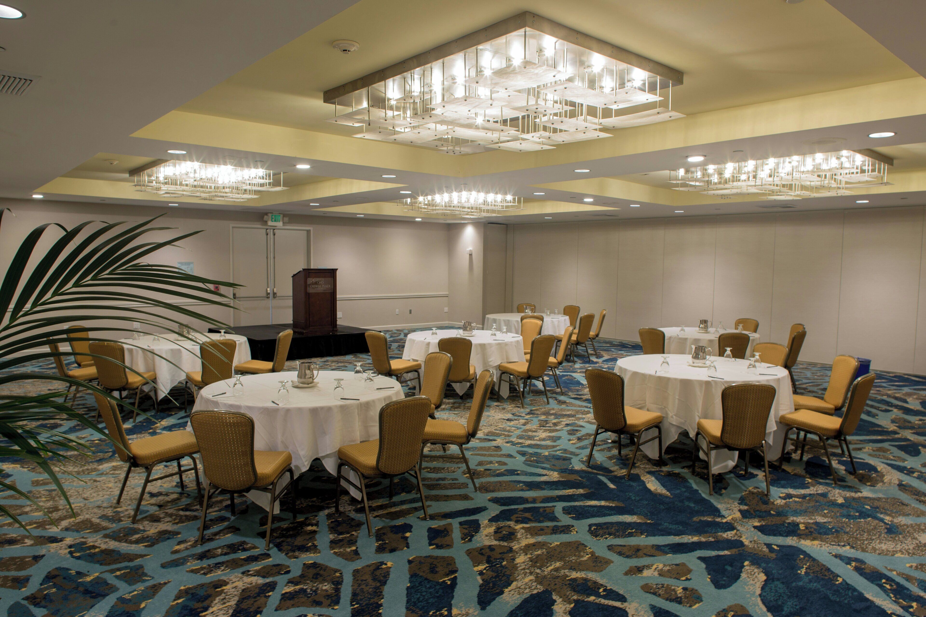 A conference room with round tables, chairs, and a chandelier.