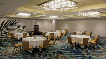 A conference room with round tables, chairs, and a chandelier.