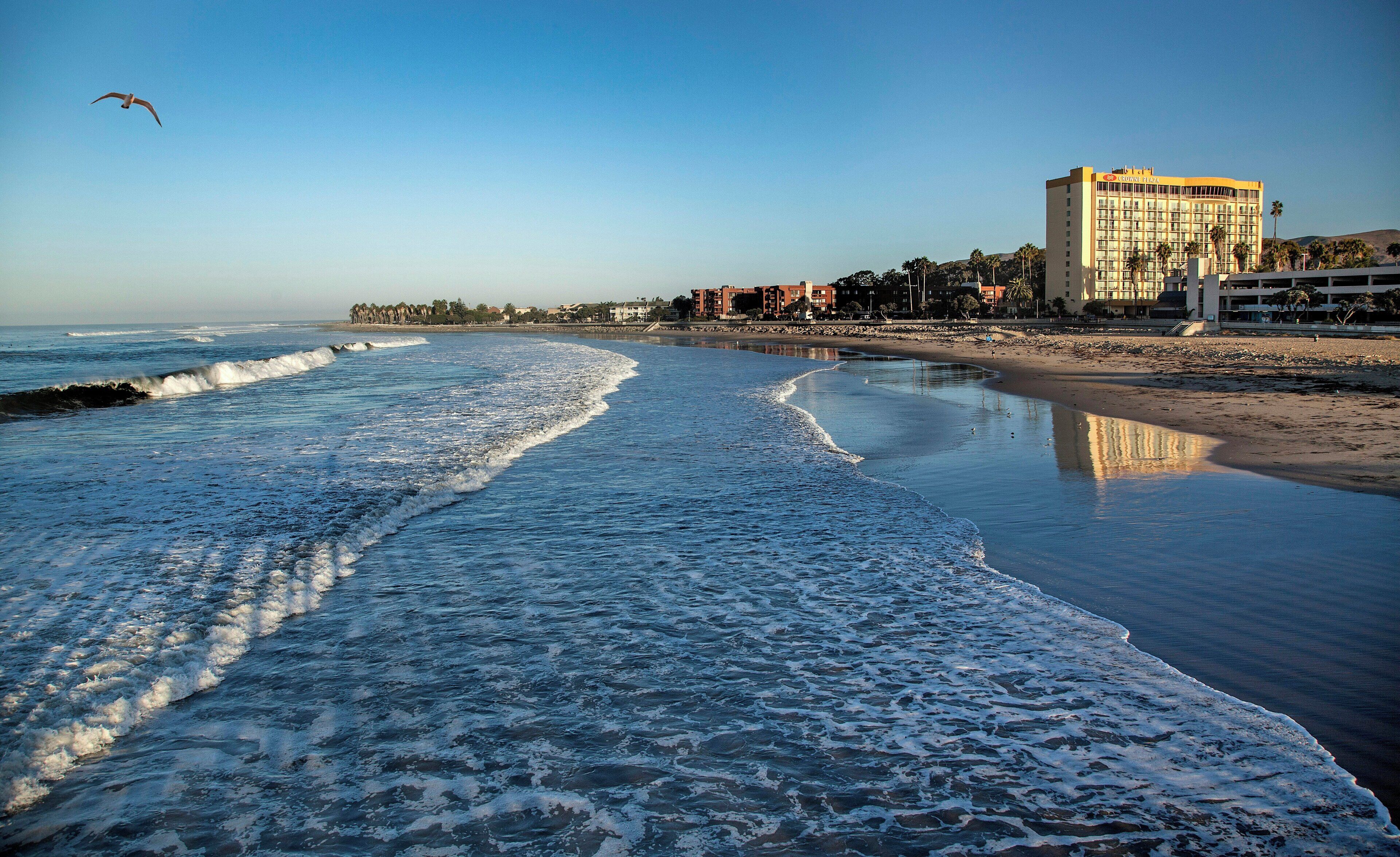 A beachfront hotel with a sandy beach and ocean waves.