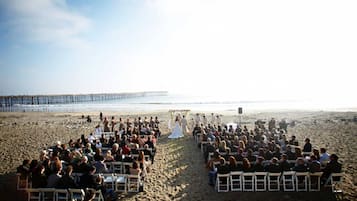 Une cérémonie de mariage sur la plage, les invités étant assis en rangées, face à l’allée.