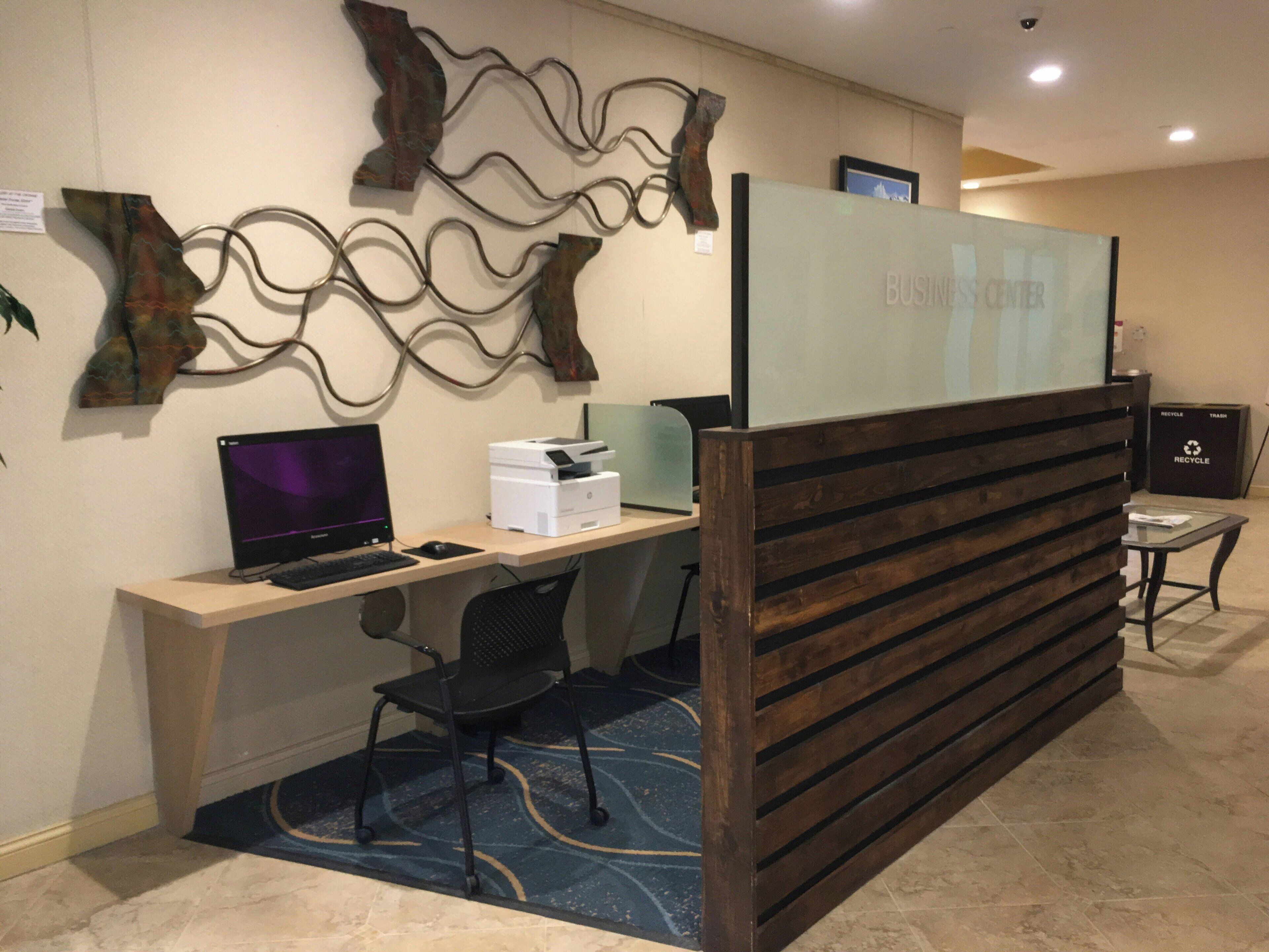 A reception area with a computer desk, a chair, a printer, and a recycling bin.