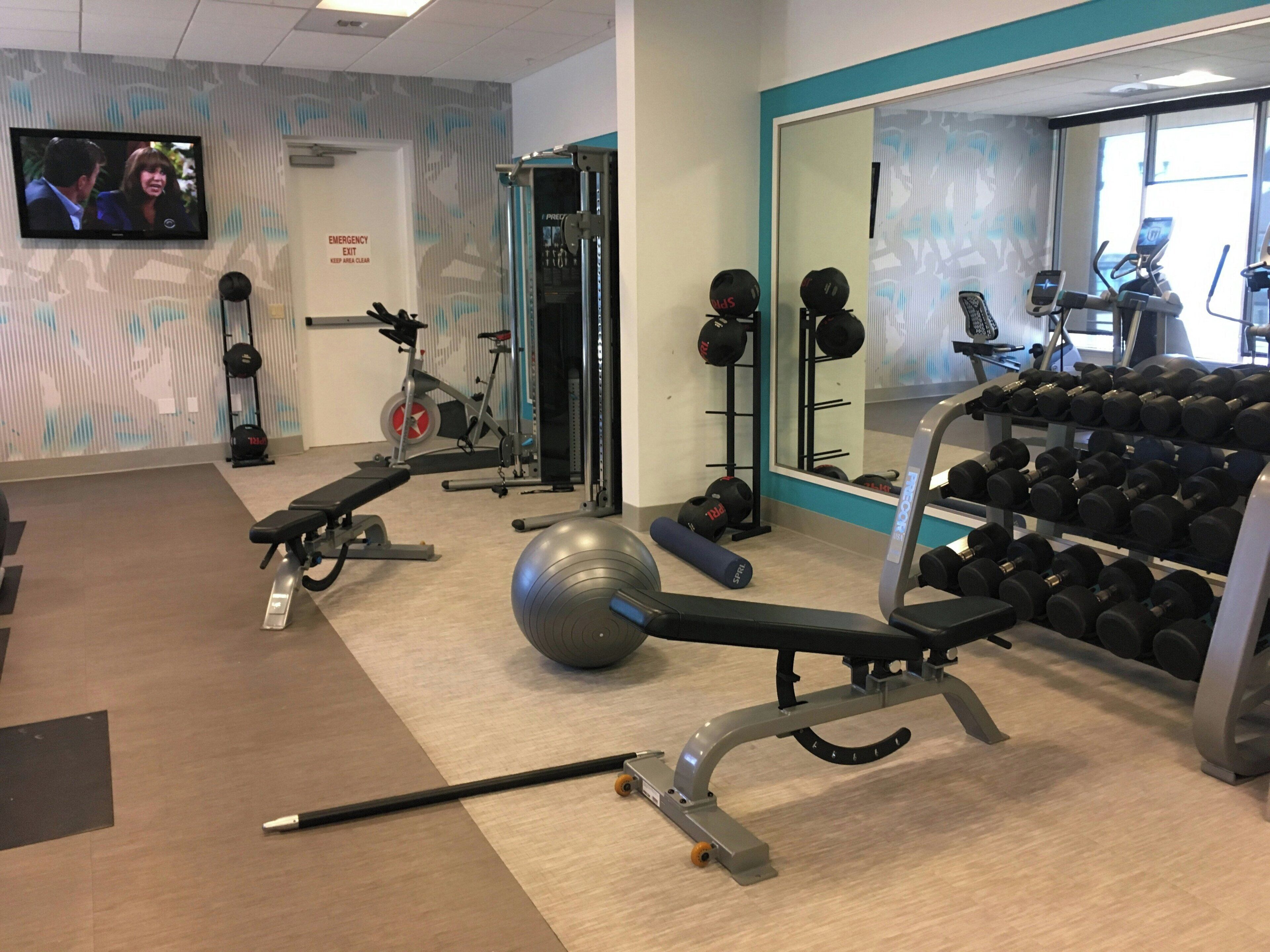Une salle de sport équipée de matériel d’exercice, d’un téléviseur et d’un miroir.