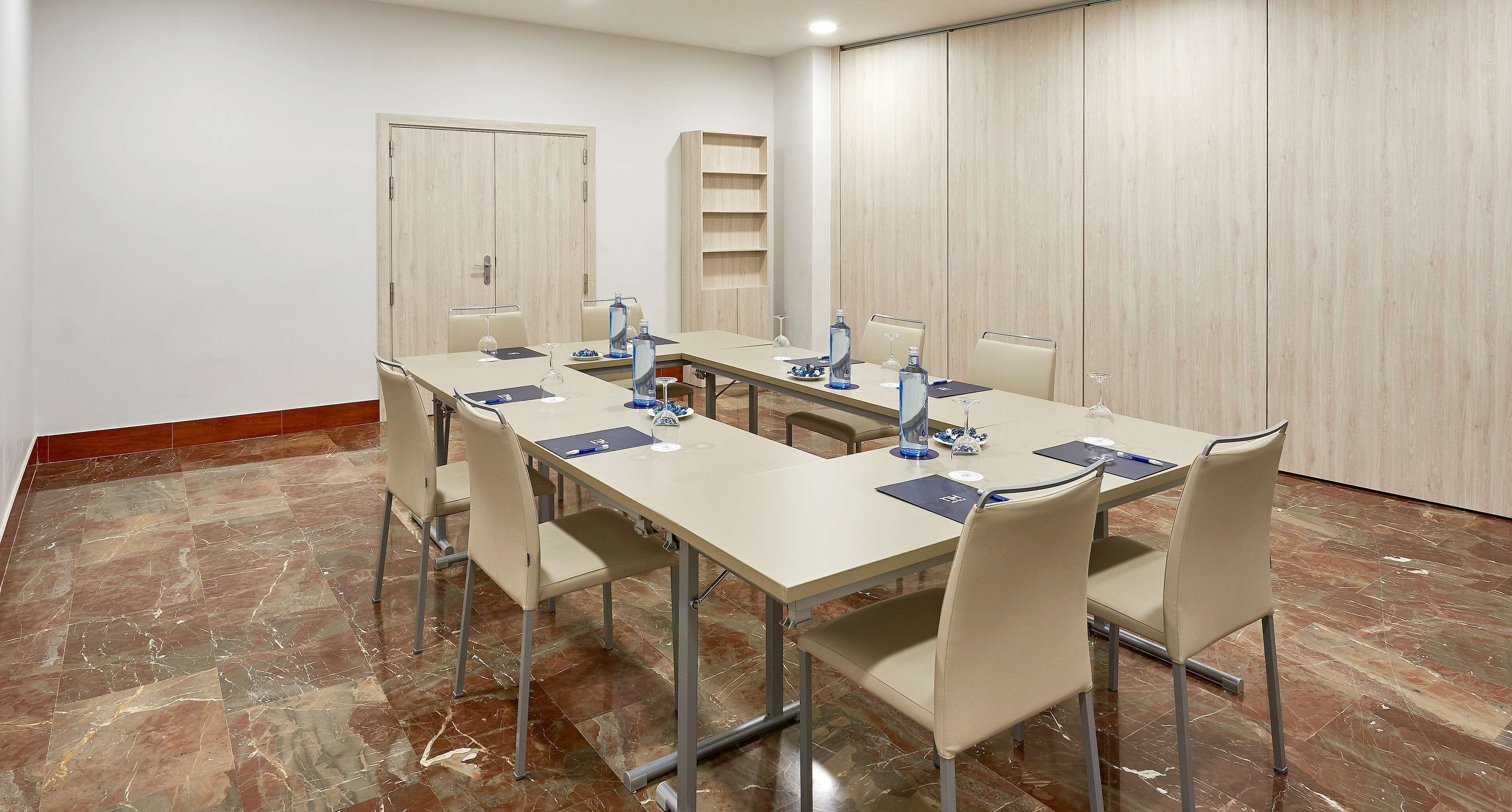 A conference room with a long table, chairs, a water dispenser, and a whiteboard.