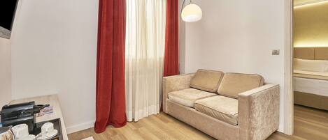 A modern living room with a beige sofa, a coffee table with a tray of cups and a kettle, and a red and white curtain.