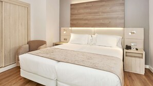 Een moderne slaapkamer met een groot bed, nachtkastjes, een stoel en een kledingkast.