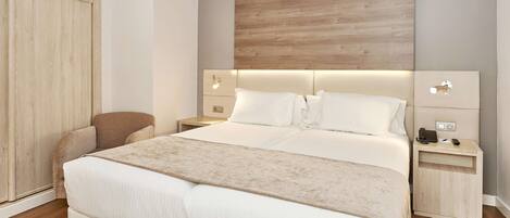 A modern bedroom with a large bed, bedside tables, a chair, and a wardrobe.
