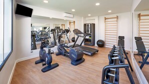 Een moderne sportschool met cardioapparatuur, gewichten en een spiegelwand.
