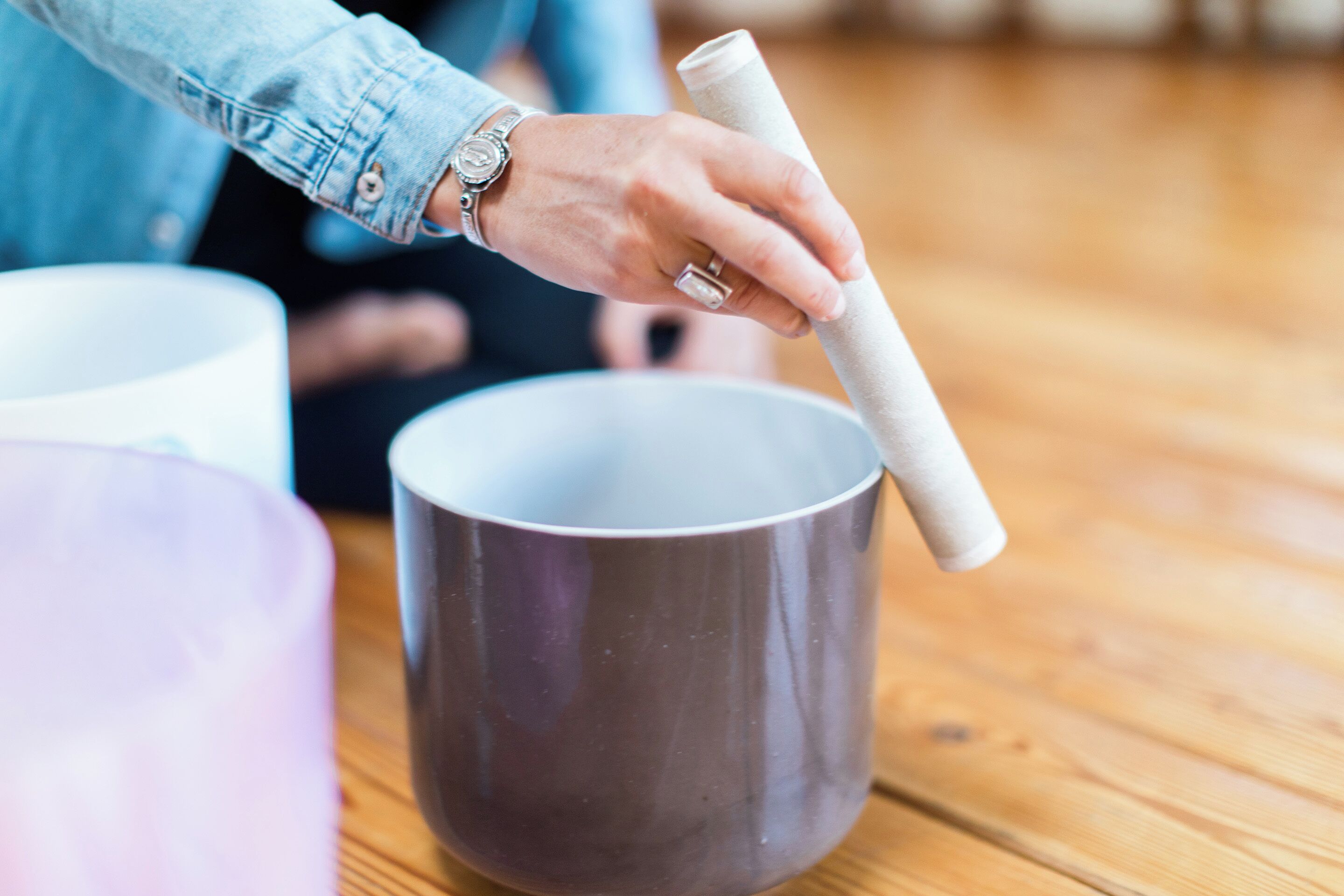 Una mano sostiene un papel enrollado junto a una taza sobre una mesa de madera.