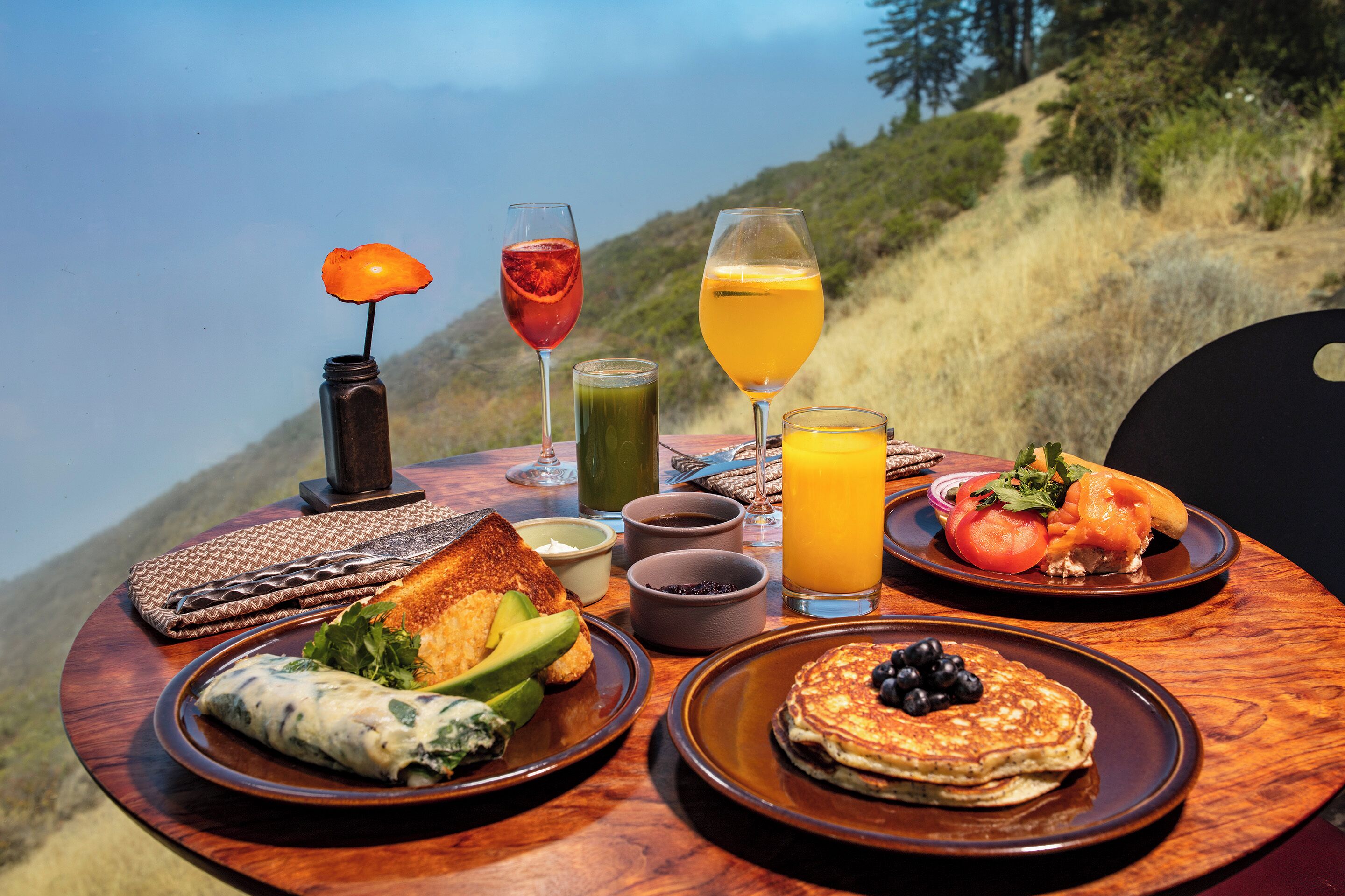 Una mesa de desayuno con platos de comida, bebidas y una vela.