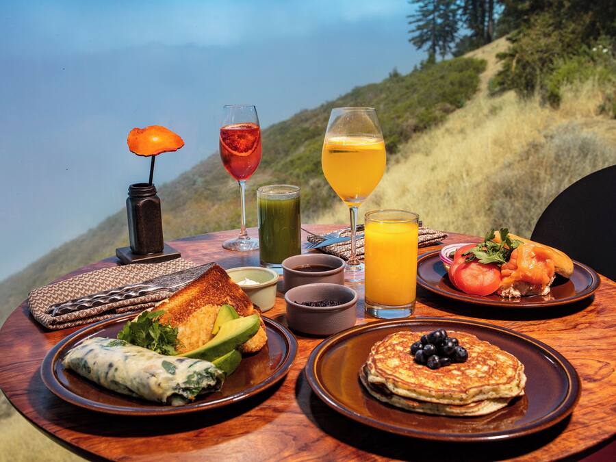 Una mesa de desayuno con platos de comida, bebidas y una vela.